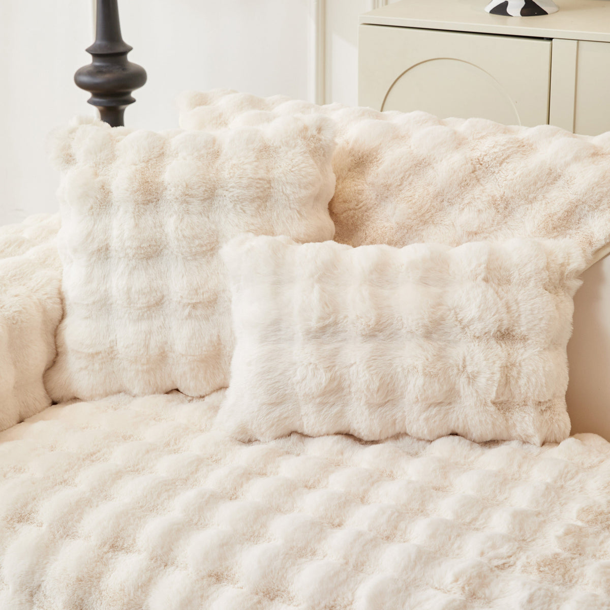 Housse de coussin EasyCover fausse fourrure molletonnée 45×45, à l'unité, Blanc crème bulles, posée sur un canapé