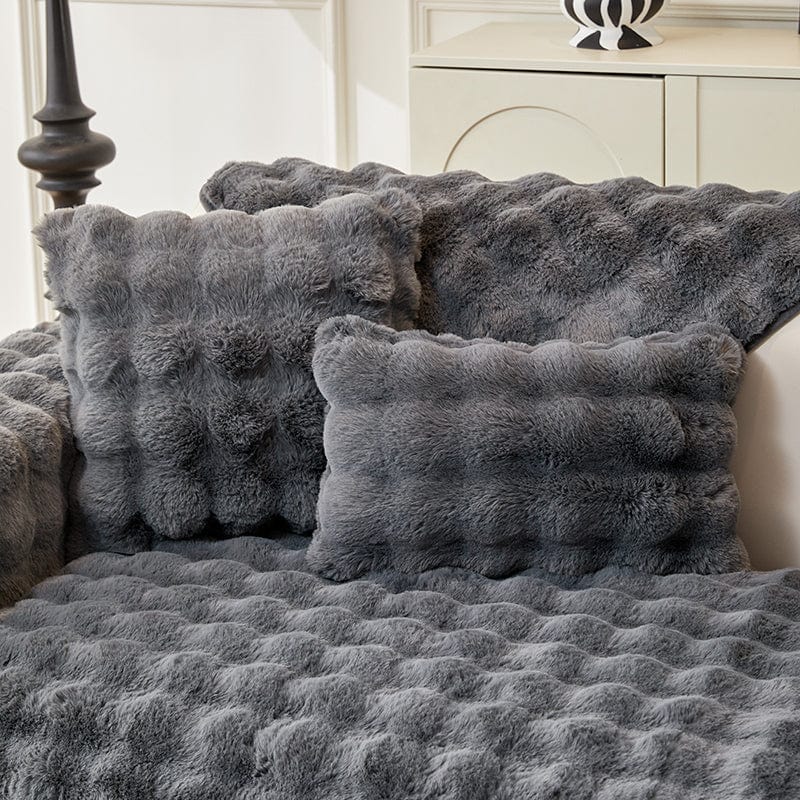 Housse de coussin EasyCover fausse fourrure molletonnée 45×45, à l'unité, Gris bulles, posée sur un canapé