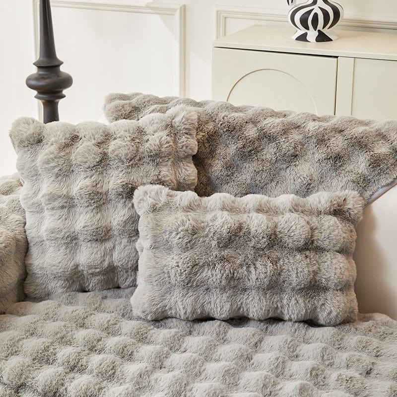 Housse de coussin EasyCover fausse fourrure molletonnée 45×45, à l'unité, Gris clair bulles, posée sur un canapé
