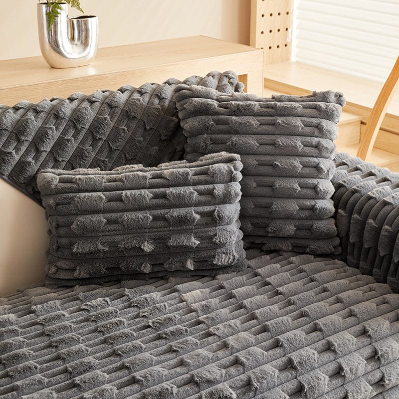 Housse de coussin EasyCover fausse fourrure épaisse 45×45, à l'unité, Gris foncé pavés, posée sur un canapé