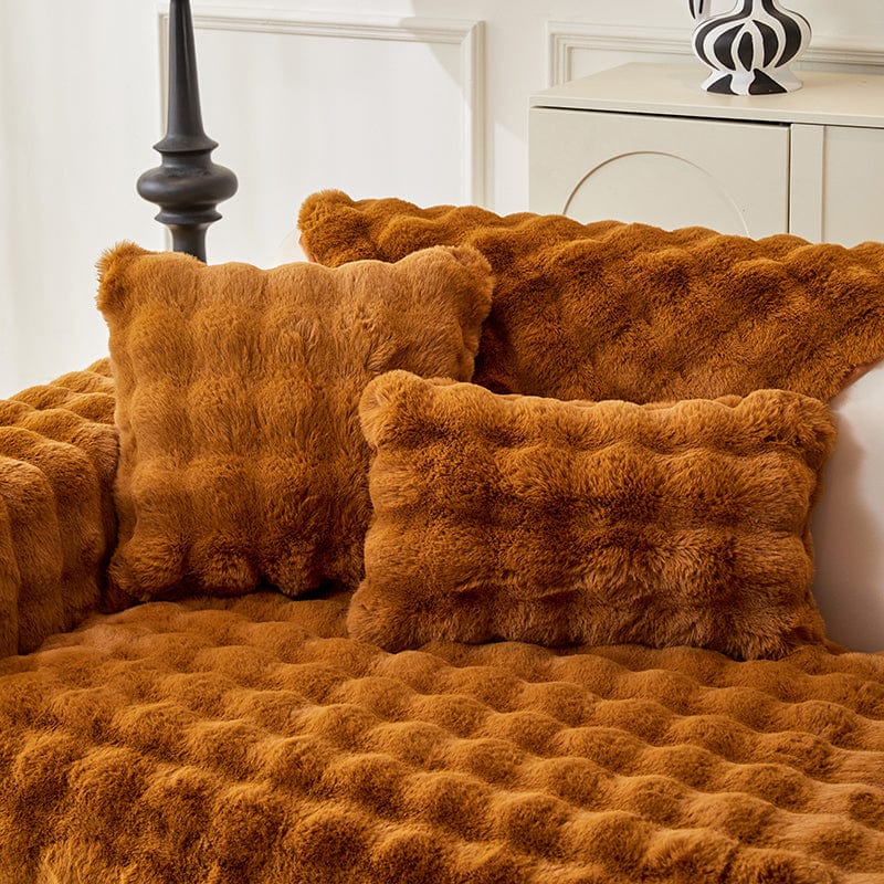Housse de coussin EasyCover fausse fourrure molletonnée 45×45, à l'unité, Marron caramel bulles, posée sur un canapé