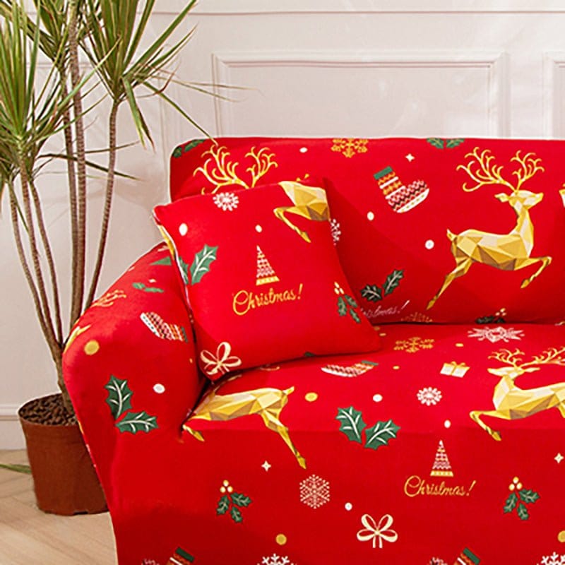 Housses de coussin de Noël 45×45, lot de 2, Rouge rennes dorés, posée sur un canapé habillé du même motif