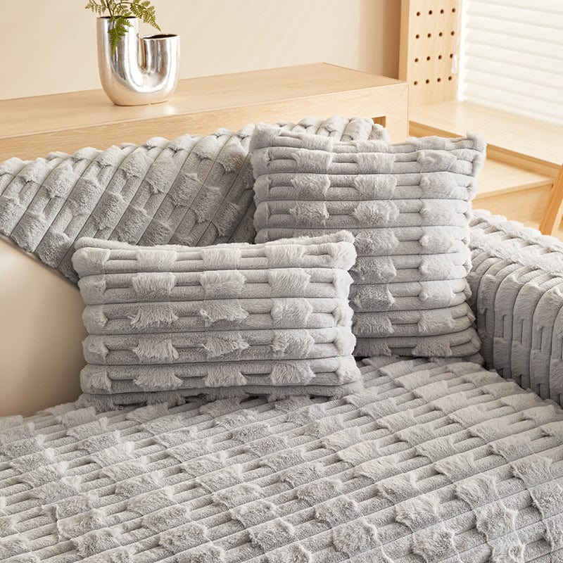 Housse de coussin EasyCover fausse fourrure épaisse 45×45, à l'unité, Gris clair pavés, posée sur un canapé