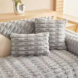 Housse de coussin EasyCover fausse fourrure épaisse 45×45, à l'unité, Gris clair pavés, posée sur un canapé