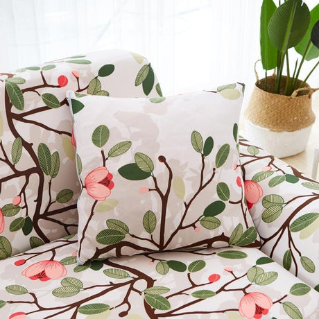 Housse de coussin extensible 45×45, à l'unité, Écru fleuri rose, posée sur un canapé